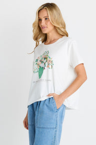 Woman wearing a white t-shirt with floral design and text, standing against a plain background
