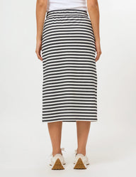 A person wearing a black and white horizontally striped midi skirt with a white drawstring waist and side pockets, paired with white sneakers, against a plain white studio background.