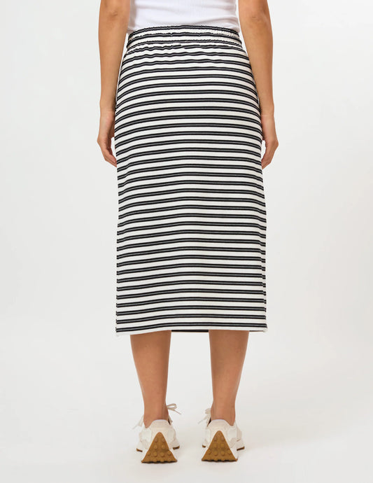 A person wearing a black and white horizontally striped midi skirt with a white drawstring waist and side pockets, paired with white sneakers, against a plain white studio background.