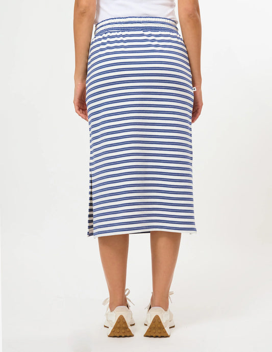 A model from the back wearing a blue and white horizontally striped midi skirt with side slits, paired with white sneakers.