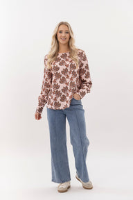 Woman wearing a floral blouse and blue jeans on a white background