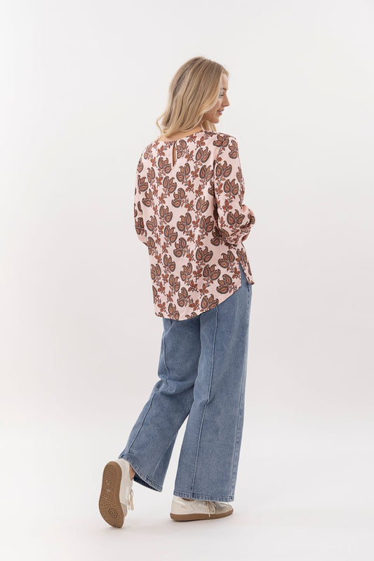 Woman wearing a floral blouse and blue jeans on a white background