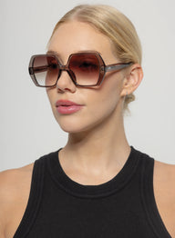 Woman wearing large sunglasses with a plain background