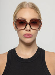 Woman wearing large sunglasses with a plain background