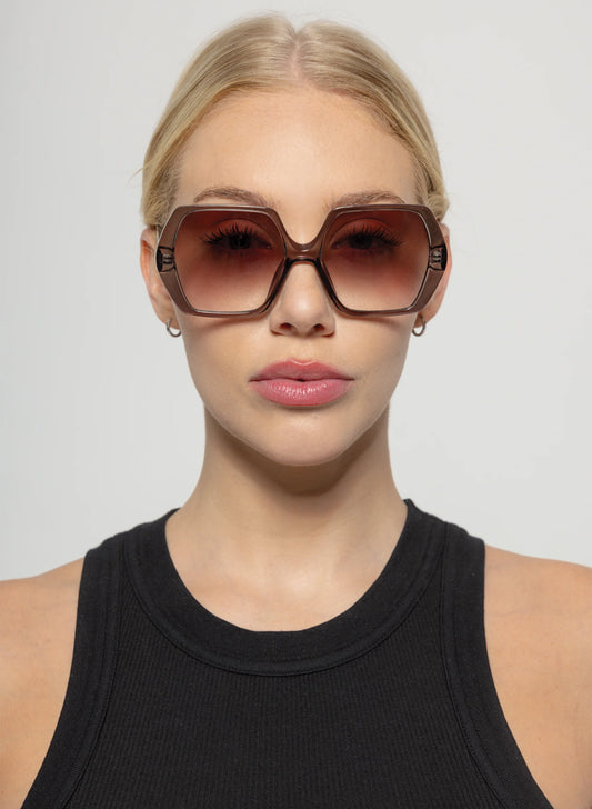 Woman wearing large sunglasses with a plain background