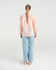 Person wearing a light pink blouse and light blue jeans on a white background