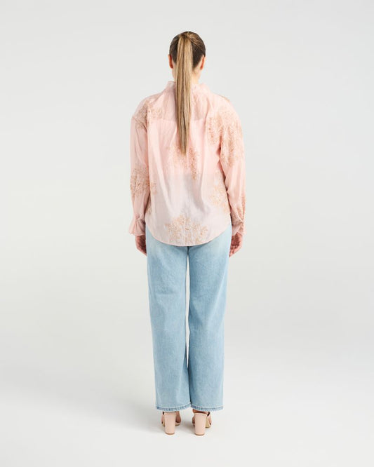 Person wearing a light pink blouse and light blue jeans on a white background