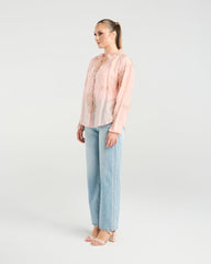 Woman wearing a light pink blouse and light blue jeans on a white background