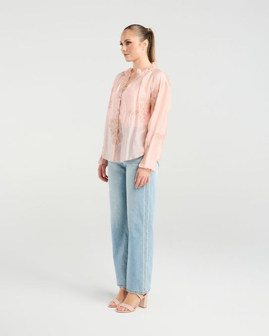 Woman wearing a light pink blouse and light blue jeans on a white background