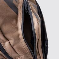 Close-up of a brown and black backpack showing a zippered compartment with black zippers and a textured fabric.