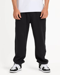 Person wearing black pants and black and white sneakers on a white background