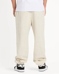Person wearing beige sweatpants and black sneakers on a white background