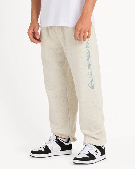 Person wearing beige sweatpants with a brand logo and black and white sneakers on a white background