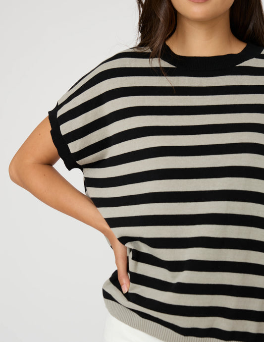 A close-up of a woman wearing a short-sleeve knit top with horizontal black and light beige stripes, cropped from the lower face to the hips against a plain light background.