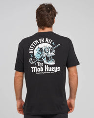 A man viewed from behind wearing a black t-shirt with a large graphic print on the back. The graphic features a white and light blue skull with a golf club, the text 'HITTIN FK ALL' arched above, and 'The Mad Hueys' below in a distressed font.