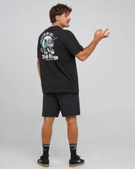 A man wearing a black t-shirt and shorts from behind, showing a large graphic print on the back with the text 'HITTIN FK ALL' and 'The MAD HUEYS'.