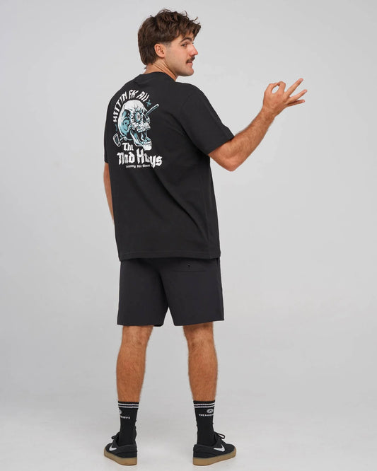 A man wearing a black t-shirt and shorts from behind, showing a large graphic print on the back with the text 'HITTIN FK ALL' and 'The MAD HUEYS'.