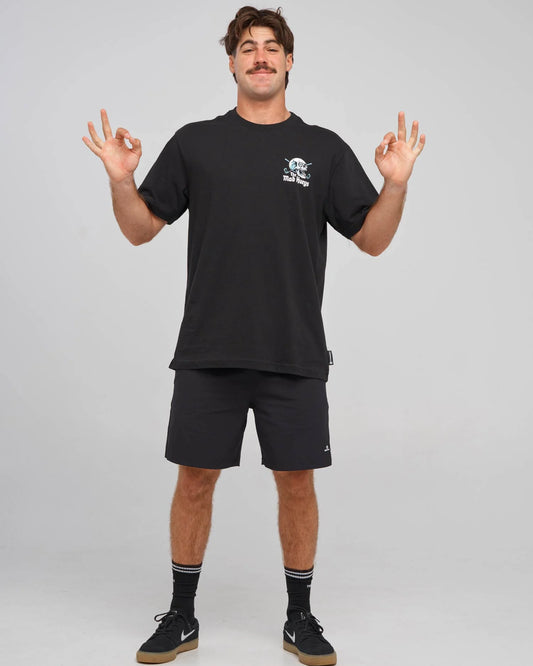A man modeling a black short-sleeve t-shirt and matching black athletic shorts against a light gray studio background. The t-shirt features a small white graphic on the left chest, and the shorts have a small white logo near the hem.