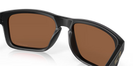 Black sunglasses with brown lenses on a reflective surface