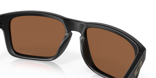 Black sunglasses with brown lenses on a reflective surface