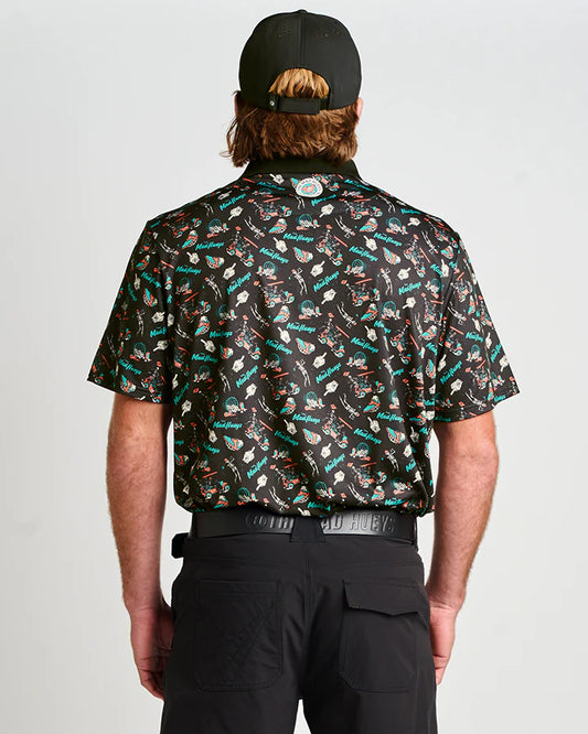 Person wearing a patterned shirt and black cap on a plain background