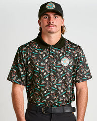 Man wearing a patterned shirt and cap with visible branding on a plain background