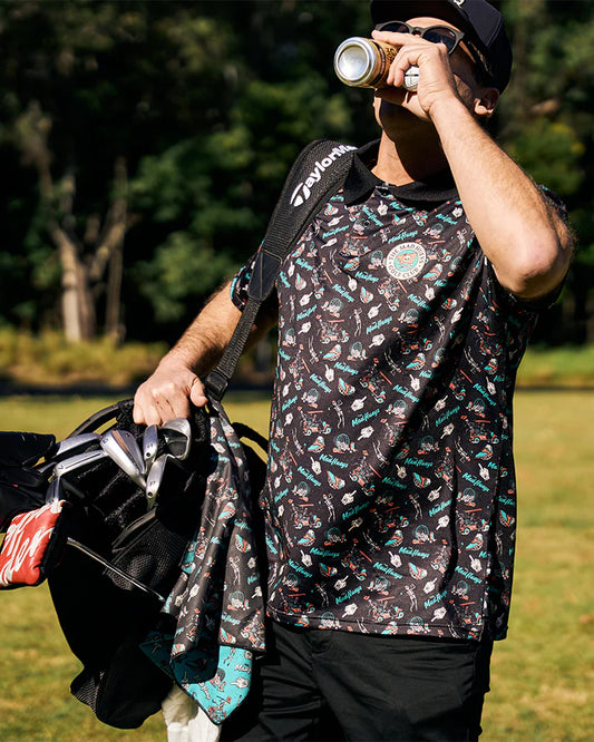 Person holding a golf bag and drinking from a can in a grassy outdoor setting
