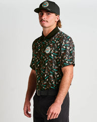 Man wearing a patterned shirt and cap on a plain background