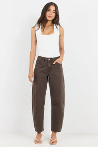 Woman wearing a white tank top and brown high-waisted jeans on a white background
