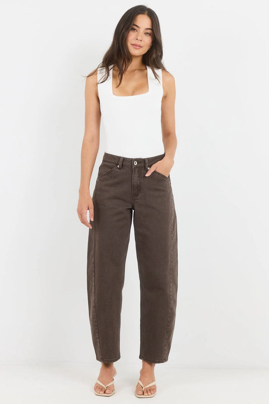Woman wearing a white tank top and brown high-waisted jeans on a white background