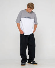 Person wearing a gray and white t-shirt with black pants on a white background