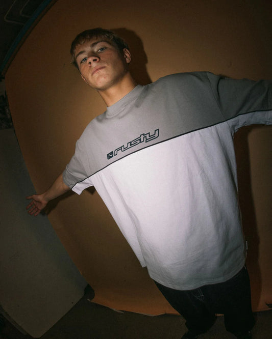 Person wearing a gray and white t-shirt with a logo on a plain background