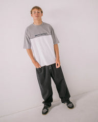 Person wearing a gray and white t-shirt with black pants on a light gray background