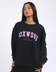 Person wearing a black sweatshirt with 'FOXWOOD' printed in pink on a white background