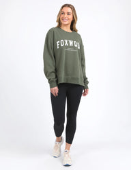 Woman wearing a green sweatshirt with 'FOXWOOD' printed on it against a white background