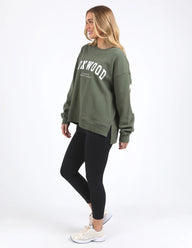 Woman wearing a green sweatshirt with text and black leggings on a white background