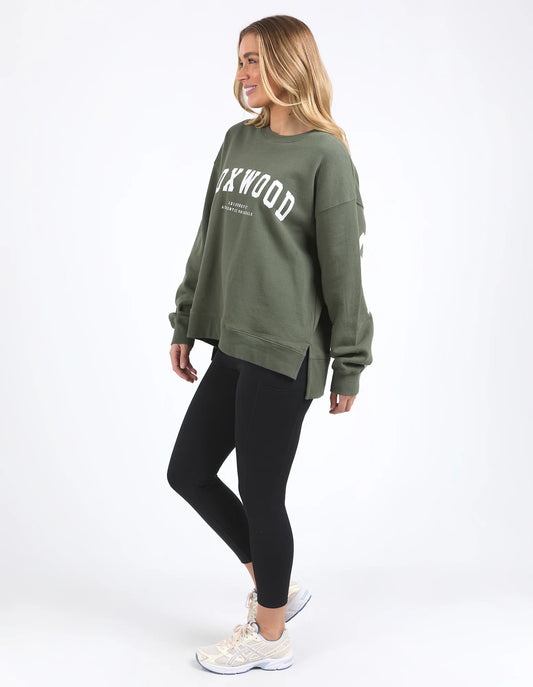 Woman wearing a green sweatshirt with text and black leggings on a white background