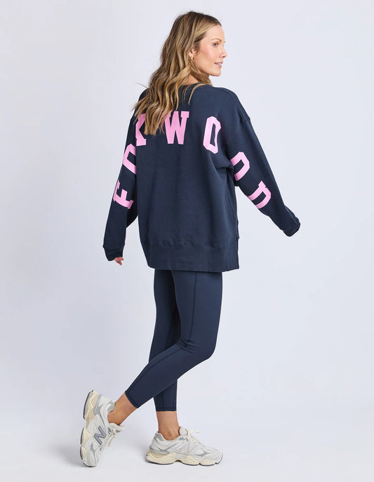 Woman wearing a navy sweatshirt with pink text and matching pants on a white background