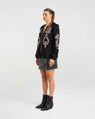 Woman wearing a black embroidered blouse with a white background