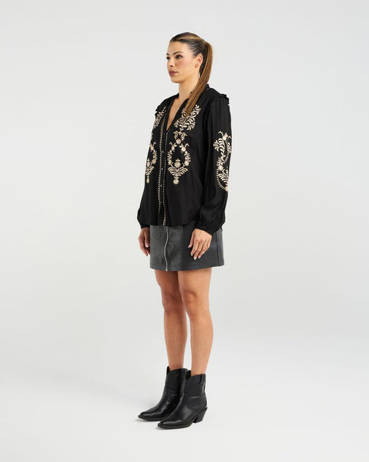 Woman wearing a black embroidered blouse with a white background