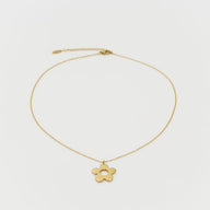 Gold necklace with a flower pendant on a light gray background