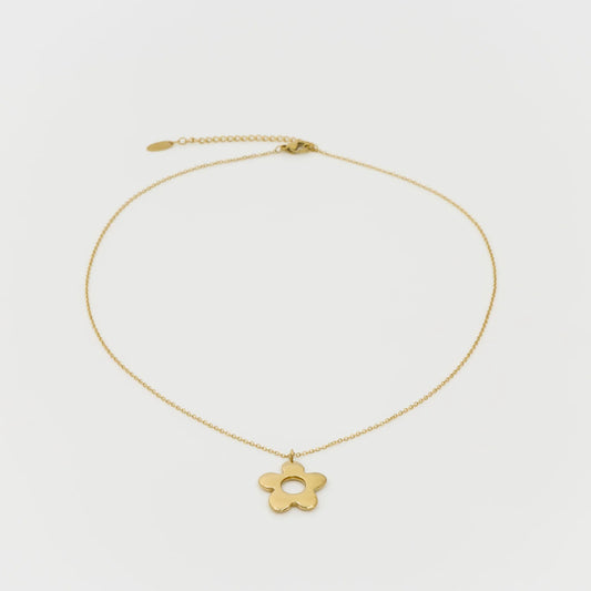 Gold necklace with a flower pendant on a light gray background