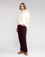 Woman wearing a white sweater and dark red pants on a white background