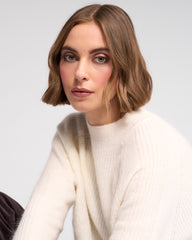 Woman wearing a white sweater against a light gray background