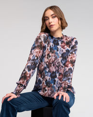 Woman wearing a long-sleeve, multicolored floral blouse against a plain background