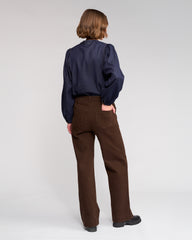 Person wearing a navy shirt and brown pants on a white background