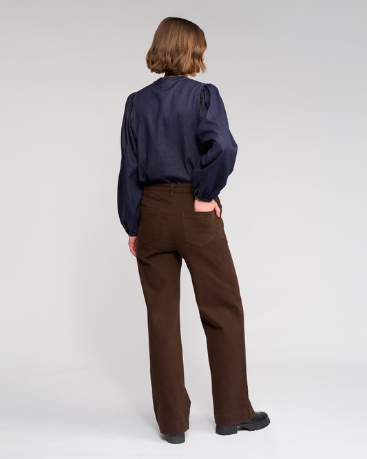 Person wearing a navy shirt and brown pants on a white background
