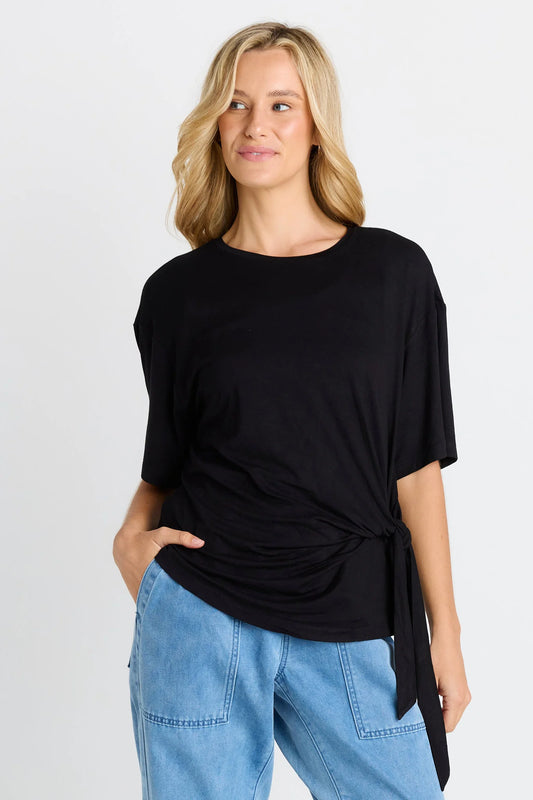 Woman wearing a black top and blue jeans on a light gray background
