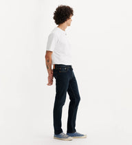 Person wearing dark blue jeans and a white shirt on a light gray background