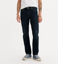 Person wearing dark blue jeans and white sneakers on a white background